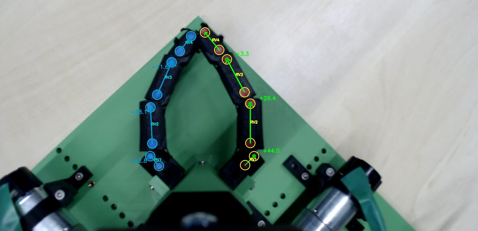 Top view of both robotic fingers with colour-coded markers, detected segment vectors and the computed joint angles overlaid in green and blue.